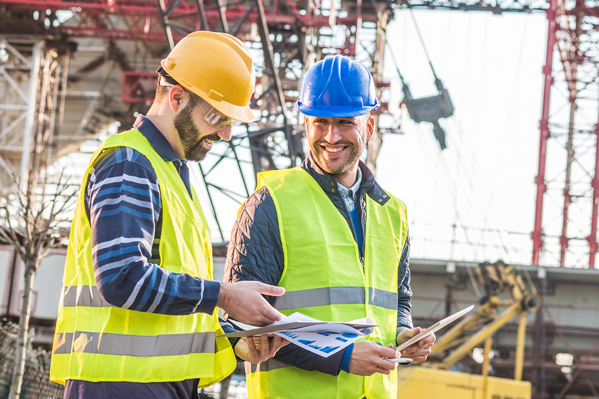 Engineers and contractors on construction site, following the progess of bridge and road infrastructure development. Two experts on construction platform in reflective wear with hardhats discussing project phases and successful previous developments. Image taken with Nikon D800 and 85mm lens, developed from RAW in XXXL size. Location: Central Europe, Europe
